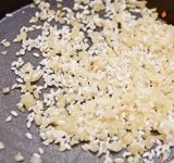 К луку добавьте рис, перемешайте, чтобы весь рис был в масле (при необходимости добавьте еще). Готовьте на слабом огне, помешивая, в течении 1 минуты.	