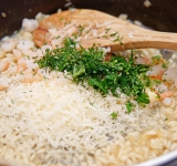 Пока рис готовится, порежьте креветки на небольшие кусочки (оставьте парочку на украшение) и измельчите зелень. Холодное масло порежьте на небольшие кусочки. 
Как только рис приготовится, снимите сковороду с плиты и добавьте креветки, зелень, масло и тертый сыр в рис, перемешайте и сразу же подавайте. 
Приятного аппетита!	