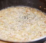 Налейте вино и готовьте, помешивая, пока оно не выпарится. В это время бульон налейте в маленькую кастрюльку и поставьте на огонь, доведите до кипения и держите на слабом огне.	