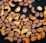 Изюм залейте горячим зеленым чаем (или водой) на 7-10 минут. Орехи положите на противень в один слой и поставьте в духовку на 5 минут, затем достаньте противень, перемешайте орехи и снова поставьте в духовку на 5 минут. Слегка охладите.	