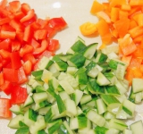 Болгарские перцы очистите от плодоножки и семян, нарежьте вместе с огурцом на кусочки по 1-2 см.