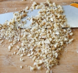 Чернослив залейте водой или зеленым чаем на 10 минут. Затем слейте воду, чернослив осушите и порежьте на кусочки по 2 см. Измельчите грецкие орехи.	