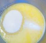 Взбейте растопленное масло с сахаром и ванильным сахаром (или эссенцией, если используете).	