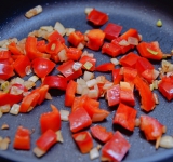 Перец очистите от плодоножки и семян и порежьте на небольшие кусочки. Добавьте к луку и готовьте еще 3 минуты.	