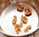 Примерно третью часть орехов обжарьте на маленькой сковороде без масла в течении 4-5 минут. Переворачивайте, чтобы орехи не сгорели. Затем порубите на небольшие кусочки.	