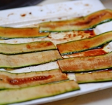 Цукини вымойте и нарежьте на тонкие длинные ломтики (как на фото). На блюдо полейте оливковое масло и бальзамический уксус, положите сверху нарезанный цукини, обваляйте в жидкости и оставьте на 5-10 минут, пока готовите начинку.	