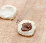 Разомните один кусочек, на центр положите немного вареной сгущенки и накройте вторым кусочком творожной массы. Обваляйте в муке.	