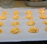 Тесто выложите на противень ложкой или с помощью кондитерского мешка. Сформируйте небольшие комочки диаметром около 3 см. Оставляйте между ними свободное расстояние (около 5 см), так как в духовке они заметно увеличатся.	