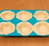 Тесто раскатать, вырезать небольшие квадратики, выложить в формочки.
На дне сделать наколы вилкой (для того, чтобы тесто не вздулось, а если оно все-таки вздуется, ничего страшного, его можно просто придавить).
Поставить в разогретую до 180 градусов духовку.
Выпекать в течение 15-20 минут.
Готовые корзиночки остудить.