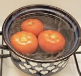 Затем добавьте вино, прибавьте огонь до максимума и готовьте, пока жидкость не испарится.  
В это время снимите с помидор кожицу и нарежьте на небольшие кусочки.	