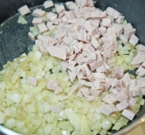 Ветчину порежьте на небольшие кусочки и добавьте к луку. Готовьте 2 минут. Снимите с огня.	