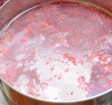 Сок отложите, а жмых поместите в кастрюлю и залейте воду, добавьте сахар. Доведите до кипения и готовьте на среднем огне около 5 минут.	