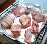 Вымойте мясо с костями и выложите на противень. Поставьте в разогретую духовку на 20 минут.