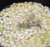 Добавьте цукини в сковороду к луку. Залейте также бульон, уксус и сушеный укроп.