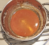 Приготовление начнем с глазури. Для этого возьмите небольшую кастрюльку. Добавьте туда сахар (30 г) и 2,5 ч.л. воды. Поставьте на слабый огонь и готовьте, помешивая, до растворения сахара. Затем прибавьте слегка огонь (до умеренно среднего) и готовьте, пока сахар не превратится в светло коричневую глазурь.  
После этого снимите с огня и сразу перелейте глазурь на дно жаропрочной емкости, в которой будете готовить этот десерт. Советую делать это быстро (глазурь быстро может застыть).	