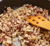 В это время помойте грибы и порежьте на небольшие кусочки, добавьте к луку и обжарьте 1 минуту. Затем залейте вино, добавьте тимьян, соль и перец, прибавьте огонь до умеренно большого, готовьте пока вино не испарится.