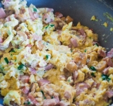 Теперь займемся приготовлением начинки: Разогрейте сковородку и выложите на нее сливочное масло, чтобы оно полностью растаяло.  
Вымойте и нарежьте грибы и обжарьте их на сковороде с маслом. 
Взбейте яйца. В мисочку с яйцами натрите сыр и тщательно перемешайте. 
Теперь сырно — яичную смесь в сковороду с грибами и колбасой, перемешайте. Вымойте, обсушите и мелко нарежьте зелень. Добавьте зелень в сковороду, поперчите и посолите, тщательно перемешайте.	