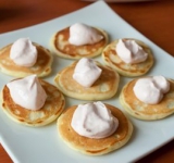 Нарежьте лосось тонкими полосками. На каждую оладью положите по 1 ч. ложке сметанного крема и по ломтику рыбы. Украсьте блинчики веточками укропа и можно подавать на стол.	