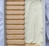 Выложите второй слой печенья, так же предварительно окунув каждое в водный раствор лимончелло.