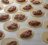 В каждый кружочек выкладываем фарш чайной ложкой на половину окружности.