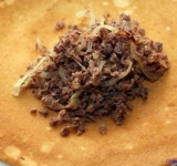 В фарш добавьте обжаренный лук и хорошенько перемешайте. На каждый блинчик, на поджаренную сторону положите столовую ложку начинки.	