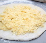 На большую лепешку выкладываем четверть тертого сыра с яйцом, равномерно распределяем начинку по лепешке, оставив свободное место по краям.	