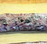 Тесто раскатываем на полоски шириной примерно 15 см (если тесто раскатанное, то просто нарезаем прямоугольники). Длина прямоугольника должна быть равна длине раскатанной колбаски. На каждый пласт теста укладываем колбаску. Края пласта смазываем взбитым яйцом и заворачиваем рулет, швом вниз.