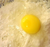 Высыпаем половину муки, размешиваем и добавляем яйцо, еще раз хорошо размешиваем массу.	