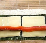 Нарезаем кусочками семгу и выкладываем ломтики по середине заготовки, вдоль листа нори.