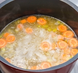 Затем все переместите в кастрюлю, добавьте горячий бульон, доведите до кипения и готовьте на слабом огне около 10 минут.