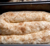 Хорошо смазываем форму сливочным маслом и выкладываем на него рулет. Оставляем рулет в таком виде на 30 минут, чтобы тесто еще немного поднялось. Смазываем пирог взбитым яйцом и посыпаем смесью сахара, корицы и кардамона.