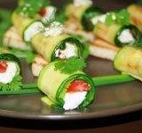 Когда цукини остыли на один конец капаем каплю масла, кладем пару кусочков чеснока, чайную ложку творожного сыра, веточку кензы и тоненькую полоску помидора. Рулетик скручиваем. Сверху рулет украшаем капелькой сыра и зеленью.