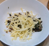 Грибы и зелень переложите в миску и добавьте тертый сыр вместе с раздавленным чесночком, посолите и поперчите.