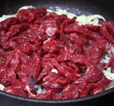 К луку добавляем мясо, посыпаем солью и перцем, и жарим на сильном огне 5-6 минут, при постоянном помешивании.