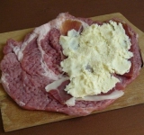 Поверх мяса укладываем кусочки сыровяленого окорка и смазываем каймаком и поверх выкладываем сыр.