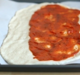 На 2/3 части теста, вдоль длинного края выкладываем томатную пасту.