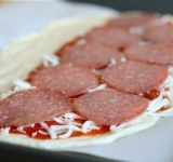 Сверху посыпаем тертый сыр, выкладываем кусочки ветчины и салями.