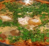 Обжаренные овощи перекладываем в кастрюлю, добавляем нарезанные на крупные дольки картофель и заливаем кипятком. Варим на среднем огне 7-10 минут. Затем добавляем в рассольник огурцы, тушёнку, специи и оставшиеся помидоры, при желании добавляем рассол. Готовим 5-10 минут.