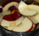 Предварительно размораживаем тесто и ставим разогреваться духовку. Воду кипятим, растворяем в ней сахар. Яблоки режем для лепестков пластами в 2-3 мм, предварительно убрав сердцевину, и опускаем в кипящую воду на 2-3 минуты. Это необходимо, чтобы яблоки стали мягкими и в дальнейшем не ломались, когда будем сворачивать розы.