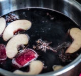 Добавляем в кипяток дольки яблока и мандарина, гвоздику и сахар. Затем добавляем вино и варим на среднем огне, периодически помешивая, не доводя до кипения.