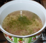 В небольшую кастрюлю помещаем картофель и обжаренную колбасу с луком, все заливаем водой и ставим на средний огонь. Солим суп, добавляем зелень, доводим до кипения.