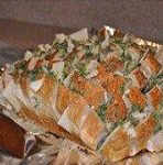 Поливаем хлеб маслом с зеленью, помещаем на противень застеленный фольгой и отправляем в предварительно разогретую духовку.