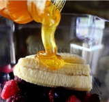 Банан почистите, порежьте на кусочки, добавьте в чашу к фруктам и йогурту вместе с цветной капустой. Все залейте медом и клюквенным соком (морсом).