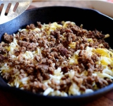 Противень либо глубокую сковороду смазываем растительным маслом и выкладываем на дно половину фарша, сверху посыпаем половиной тертого сыра.