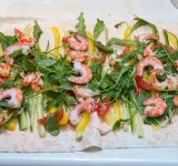 На овощи выложите креветки. Заверните лаваш в рулет.	