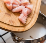 Курицу порежьте на кусочки и добавьте в кастрюлю. Готовьте еще 2 минуты.