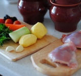 Овощи чистим, снимаем кожуру с мяса и разделяем на части, кости не удаляем. Картофель нарезаем тонкими кругляшками, помидоры разрезаем на четвертинки, чернослив разделяем пополам. Чеснок чистим и раздавливаем ребром ножа.