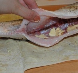 Во внутрь рыбы выкладываем кусочки сливочного масла, что прибавит блюду сочности.