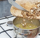 В это время порежьте мелко грибы. Ножки отдельно от шапочек. Ножки грибов добавьте к луку, добавьте также лавровый лист, тимьян, соль и перец. Готовьте на слабом огне после закипания около 20 минут, слегка прикрыв крышкой.	