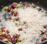 Добавьте в сковороду рис, обжарьте около 2-3 минут на слабом огне (так рис будет вкуснее). Залейте куриный бульон, добавьте специи и готовьте на слабом огне около 10 минут.	